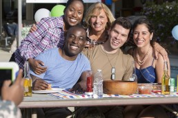 group of 5 people gathering around a table celebrating