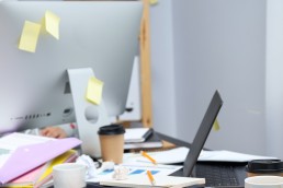 Messy workplace desk with laptop and coffee cup