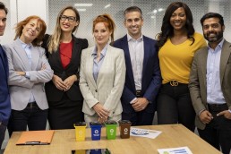 group of 7 individuals standing behind a desk dressed in business clothes