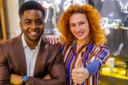 two people of mixed race smiling with a thumbs up