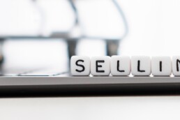 the word selling spelt out using scrabble letters placed on to of a laptop