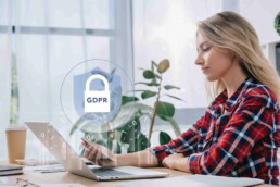 a lady sitting in front of a laptop with the letters GDPR on the screen